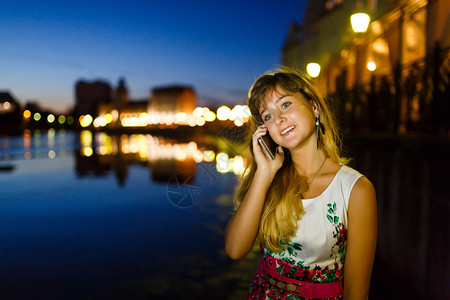 年轻漂亮的女孩在夜市用手机聊天图片