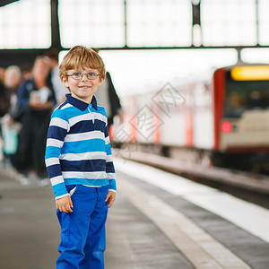 快乐的小男孩在地铁站戴眼镜男孩看着火车图片