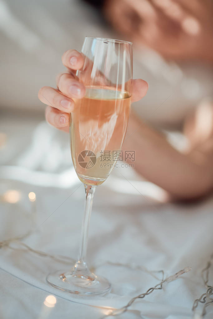 女在白床单上拿着香槟杯子与加图片