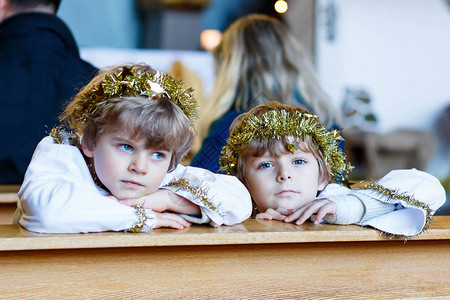 两个穿着天使服装的漂亮小孩在教堂里听圣诞故事图片