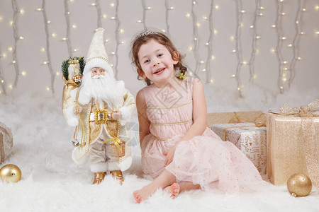 庆祝圣诞节或新年的逗人喜爱的微笑的白色种人女孩画象可爱的小可爱孩子坐在带玩具的工作室里背景