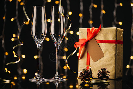空葡萄酒杯包着的圣诞节礼物丝带和松果子图片