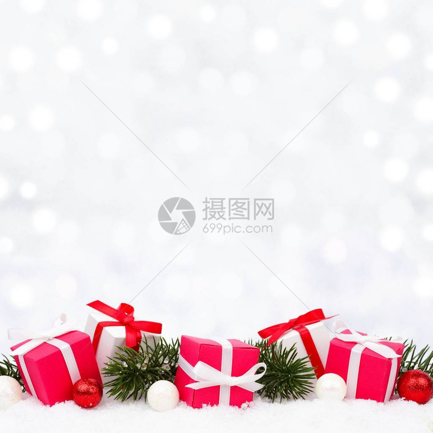 雪中的红白圣诞礼物有树枝和闪图片