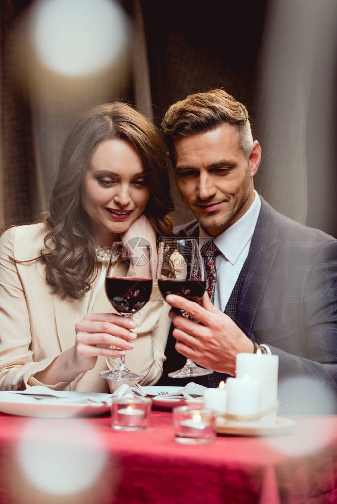 在餐厅的浪漫约会期间双一对微笑着的红酒杯夜图片