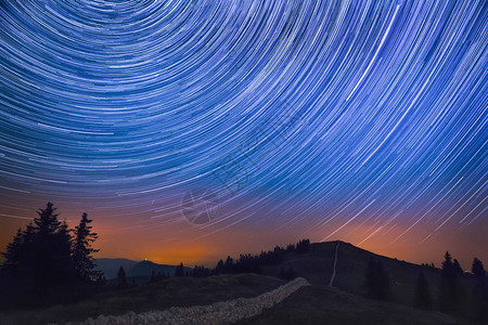 流星穿越山峦和崎岖景观的星轨图片
