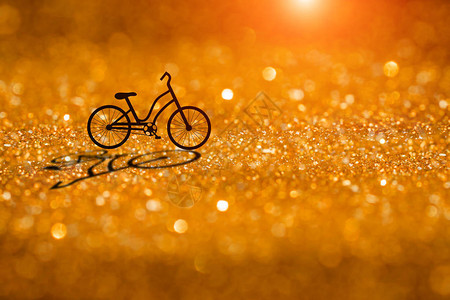 一辆自行车在橙色闪发光的闪光和散景背上的剪影图片