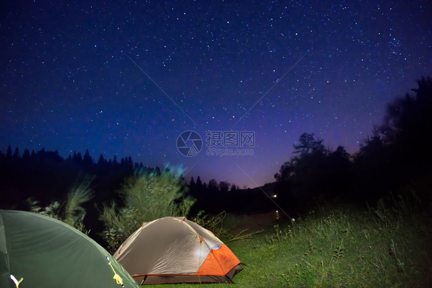 两顶明亮的帐篷在黑暗夜空下的山上图片