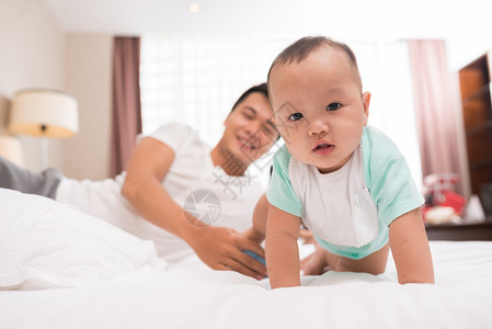 年幼的父亲和孩子在床上玩耍男图片