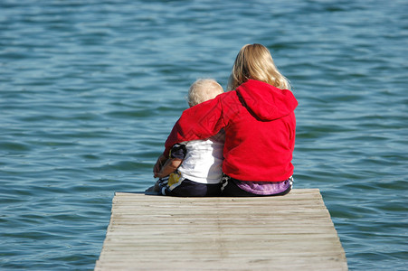 姐弟俩坐在海湾码头图片