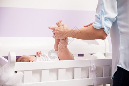 妇女举起新生婴儿的腿同时在换桌时打扫图片
