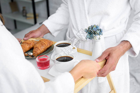一对夫妇用牛角面包和咖啡作为早餐的托盘盛着羊角面包图片