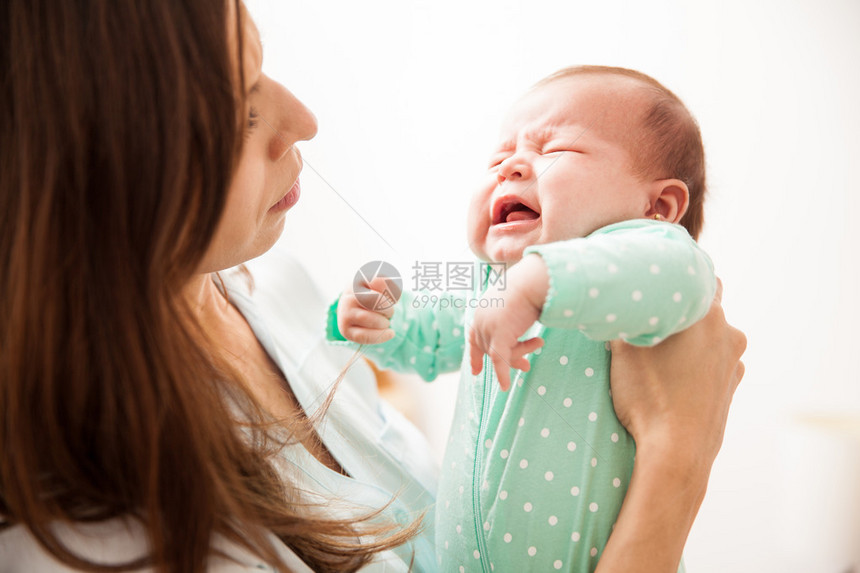 母亲把新生婴儿抱在她面前看着她哭着图片