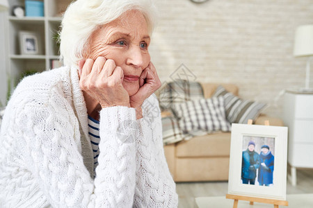 孤独的老妇人眼含泪水凝视太空的肖像图片
