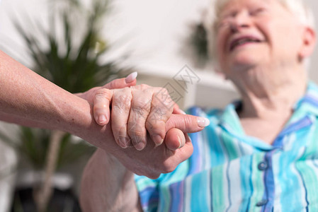 年轻女人的手牵着老妇人的手背景图片