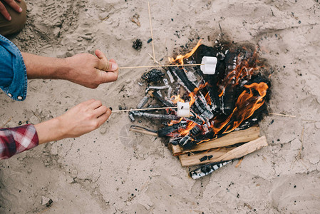在沙滩的营火上烧烤棉花糖图片