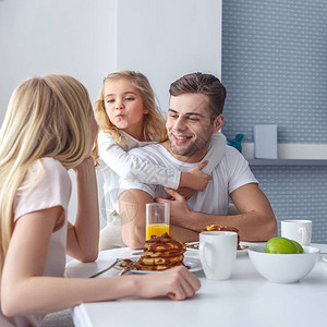 年轻幸福的家庭在周末上午吃早餐和玩图片