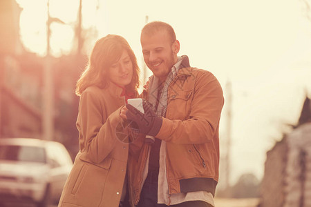 情侣用智能手机站立在模糊的街道背景上并图片