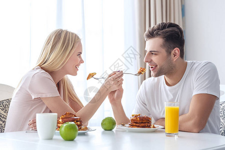 年轻夫妇用早餐互相喂食图片