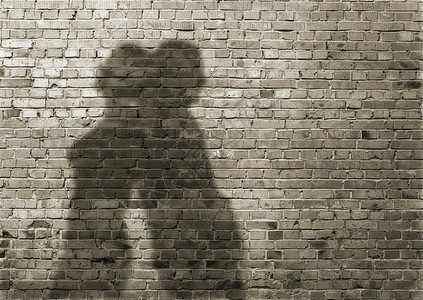 肮脏的砖墙上的男人和女人的影子图片