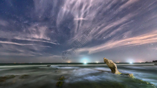 夜晚的海滩与岩石向恒星飞扬闪亮的银河系创造了一个伟大图片