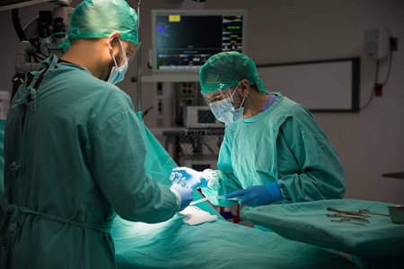 两名男外科医生在一家医院手术室对一名病人图片