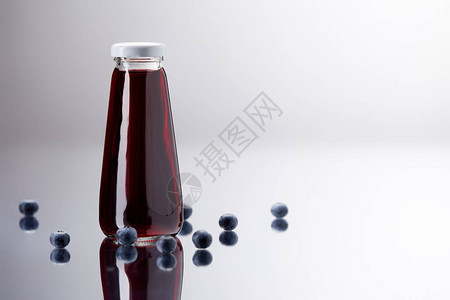 反射面上的新鲜蓝莓汁玻璃瓶图片