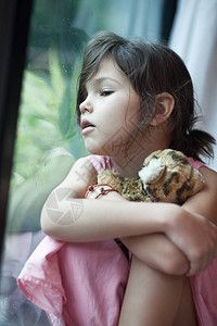 寂寞悲伤的年轻前女孩最喜爱的老虎玩具坐在窗图片