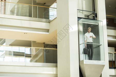 玻璃电梯里的年轻商人图片