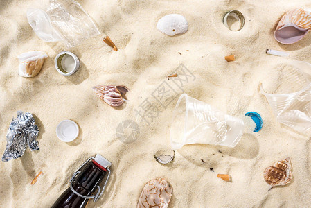 贝壳瓶盖散落的烟屁股塑料杯玻璃瓶和砂图片