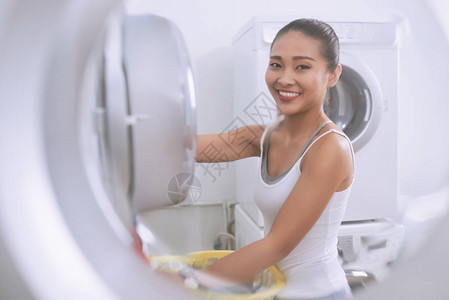 微笑的亚洲女人在洗衣机图片