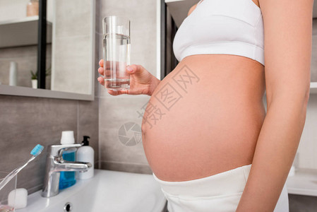 身穿内裤水杯站在浴室的孕妇图片