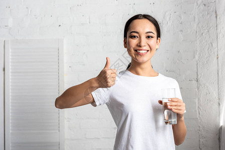 穿着白色T恤衫的年轻微笑着容的年轻女拿着杯图片