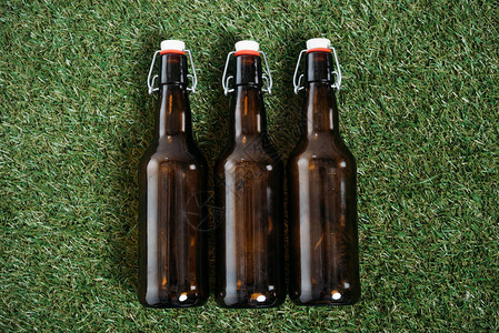 躺在草地上的三个玻璃瓶啤酒的顶视图图片