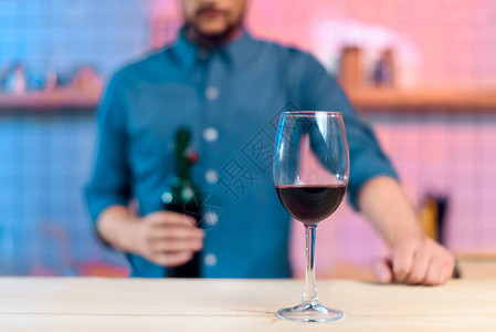 在酒吧柜台拿着酒瓶和玻璃红酒和红酒的胡图片