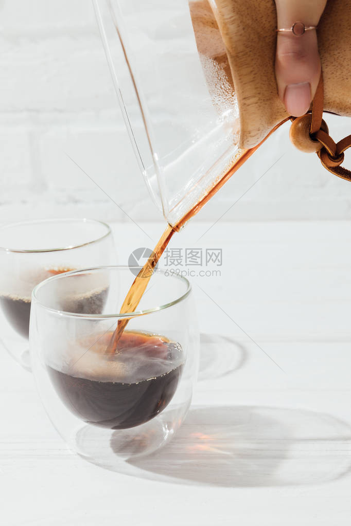 妇女将替代咖啡从化学剂倒入玻璃杯的妇图片