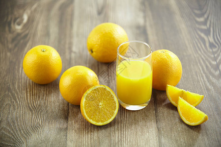 几个橙子和一杯橙汁放在硬木表面上图片