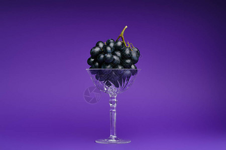紫罗兰色背景玻璃中新鲜成熟葡萄的特写视图图片