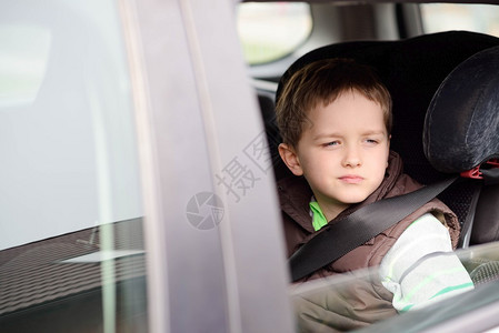 小男孩在汽车安全座上被吓着透过窗户看孩子的图片