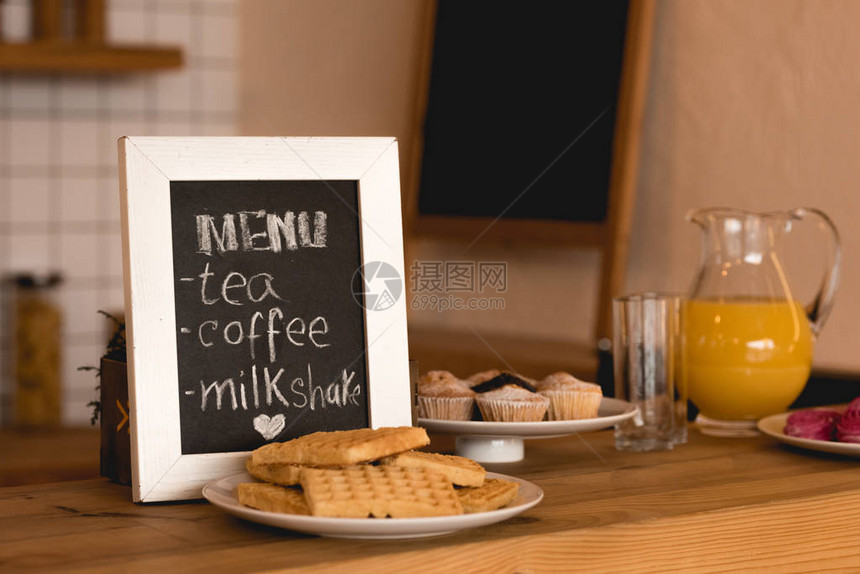 餐桌上菜单板用华夫饼和蛋糕做的菜盘子和咖啡店柜台的加新图片