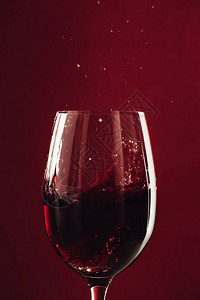 关闭在红色隔离的玻璃杯中的红酒飞溅图片