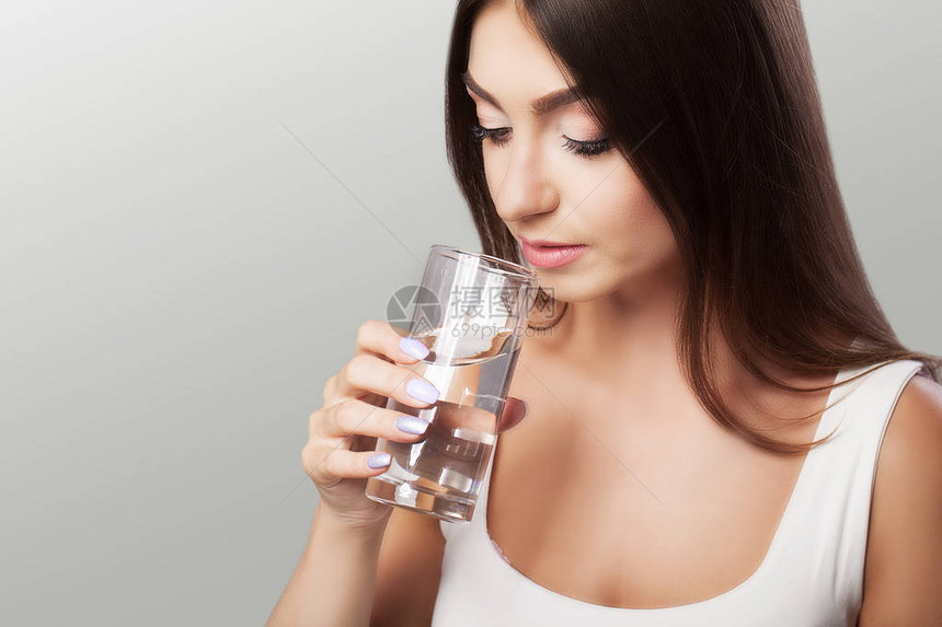喝水年轻女孩从玻璃杯里喝水每日饮水量干净的水健康和美丽的概念在图片