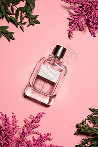 粉红色表面有花朵和叶子的香水瓶的顶部视图背景图片
