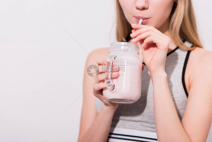 年轻女子用稻草从梅森罐子里喝奶昔的镜头图片