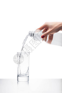 妇女用白色隔着的塑料瓶倒入玻璃中的水将图片