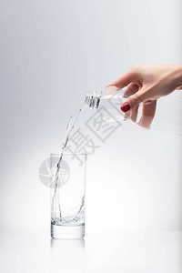 妇女用塑料瓶子倒入玻璃图片