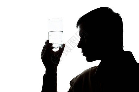 年轻人喝着一杯闪亮的水检查质量图片