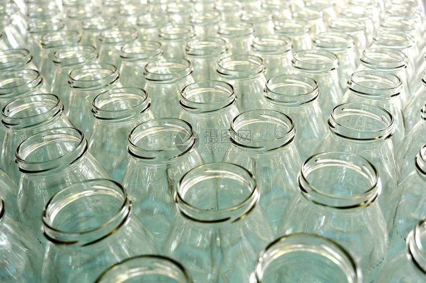 在装瓶厂工厂的生产线上或在商店出售的多排没有盖的透明空玻璃瓶图片