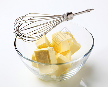 碗中的新鲜黄油块和金属搅拌器图片