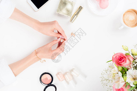 在化妆品智能手机和白色鲜花上挂着金耳环图片