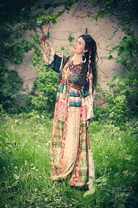 穿着长丝绸的女青年在花园穿衣站图片